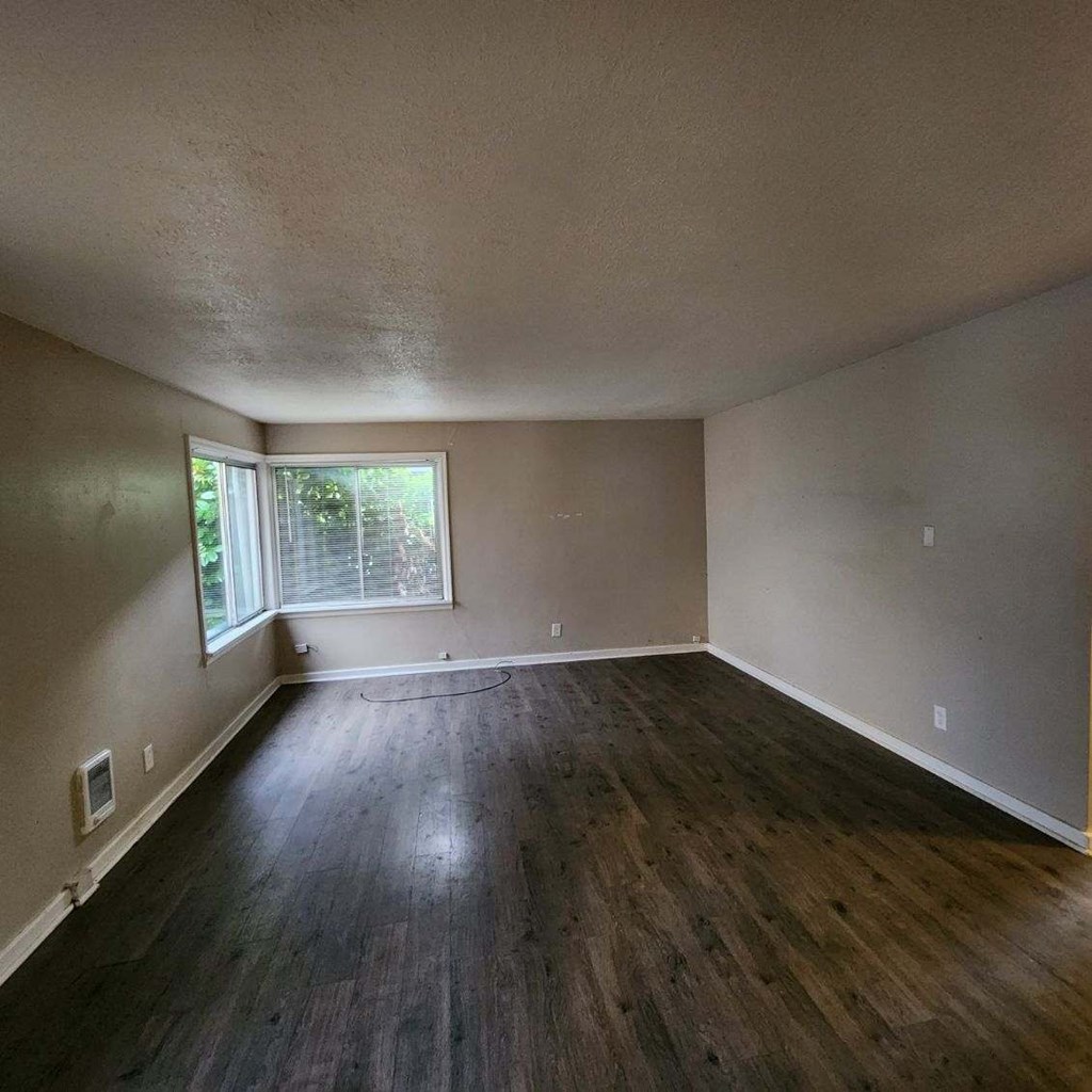 an empty living room with wood floors and a window