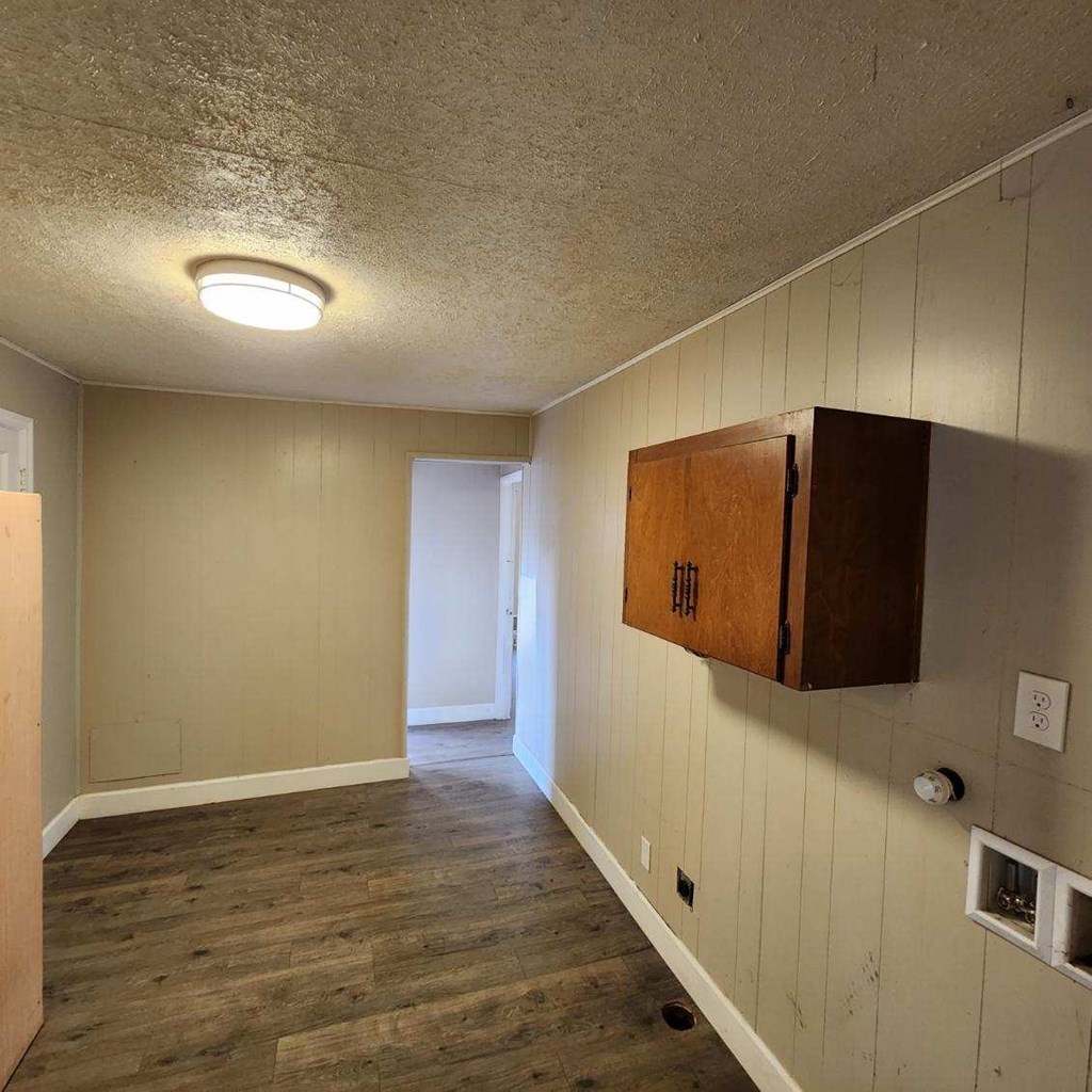 an empty room with a wooden floor and a cabinet on the wall