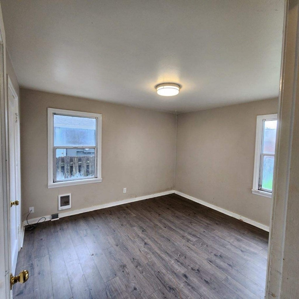 an empty room with wooden floors and a window
