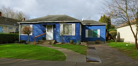 a blue house with a sidewalk in front of it