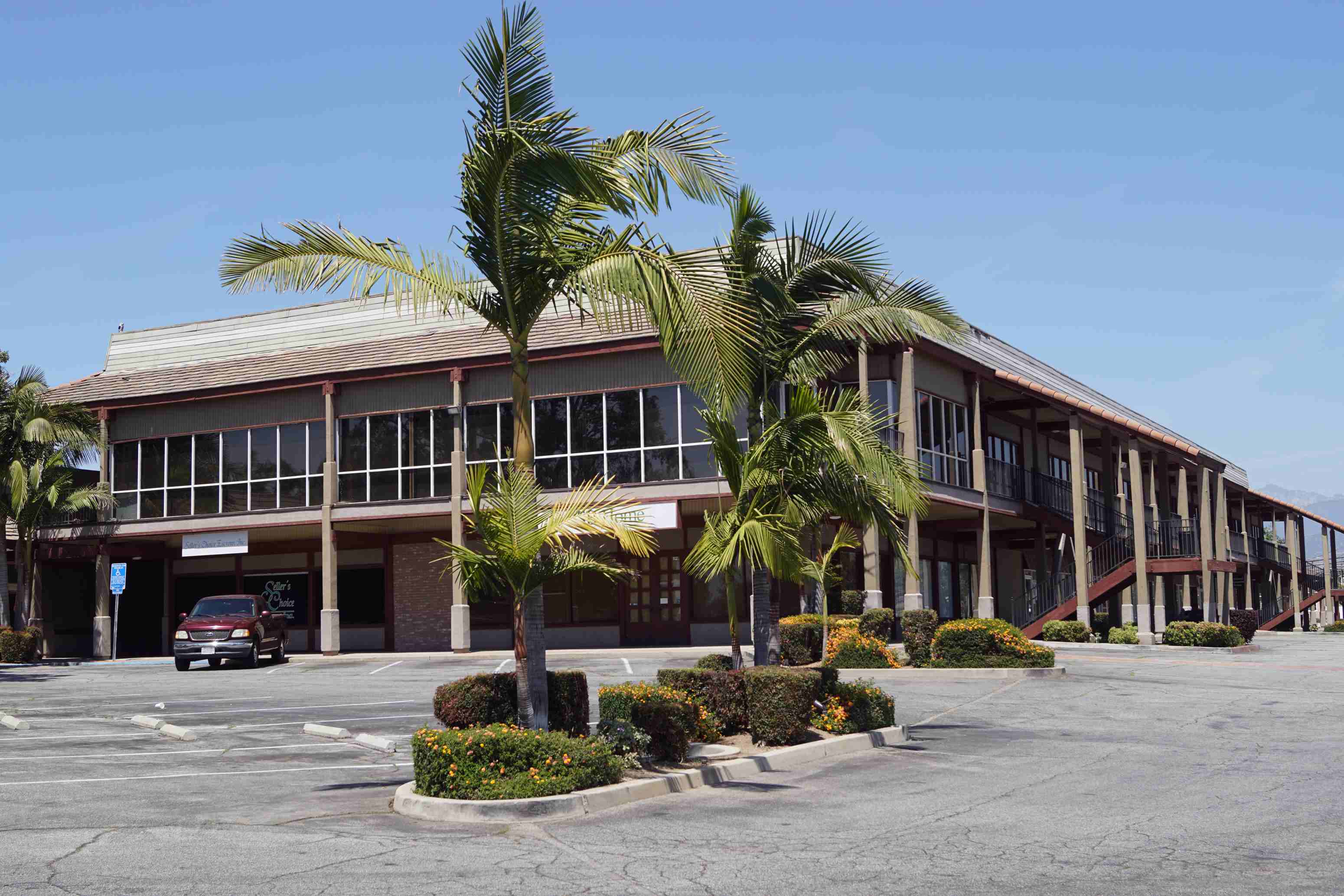 an office building with palm trees in the parking lot