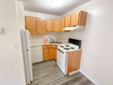 A kitchen with wooden cabinets and a white fridge.