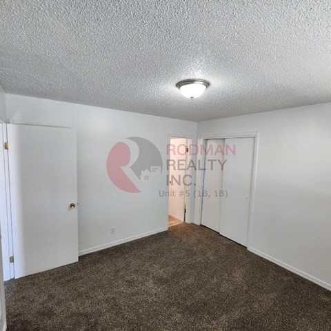 A room with carpeted floor and a white wall with a logo and text on it.