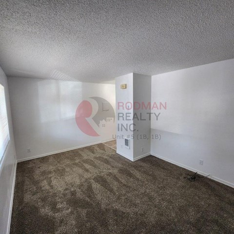 A carpeted room with a wall decal of a pink and white logo and the words "Rodman Realty Inc."