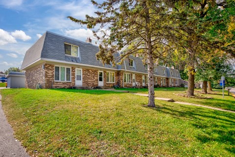 a house with a yard and trees in front of it