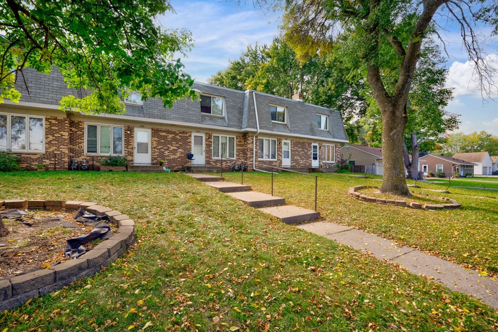 the front of a house with a tree and a sidewalk