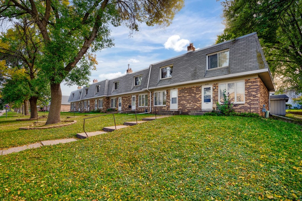 a row of houses with a lawn and trees
