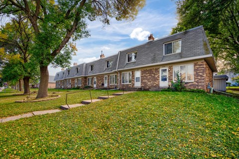 a row of houses with a lawn and trees
