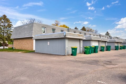 a row of rental buildings with recycling bins in front of them