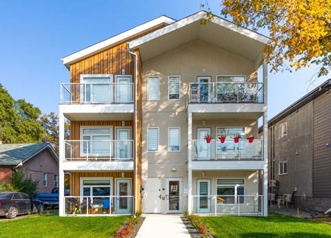 A modern two-story apartment building with balconies and a clear blue sky above.