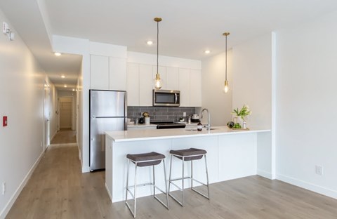 A modern kitchen with a white island and bar stools.