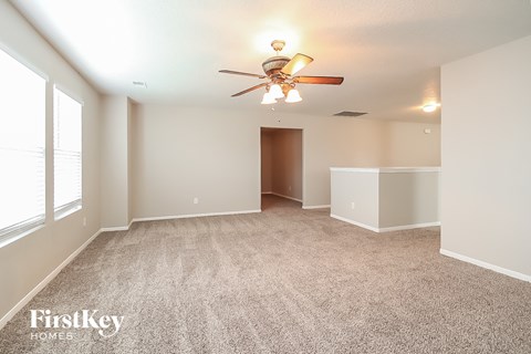 a spacious living room with carpet and a ceiling fan