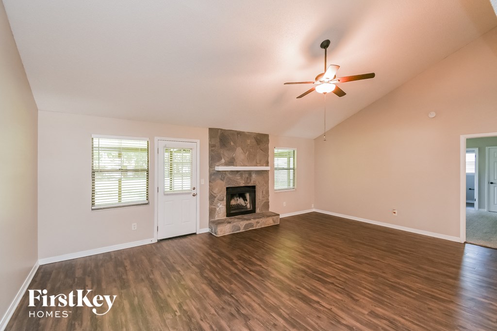 A spacious room with a fireplace and a ceiling fan.