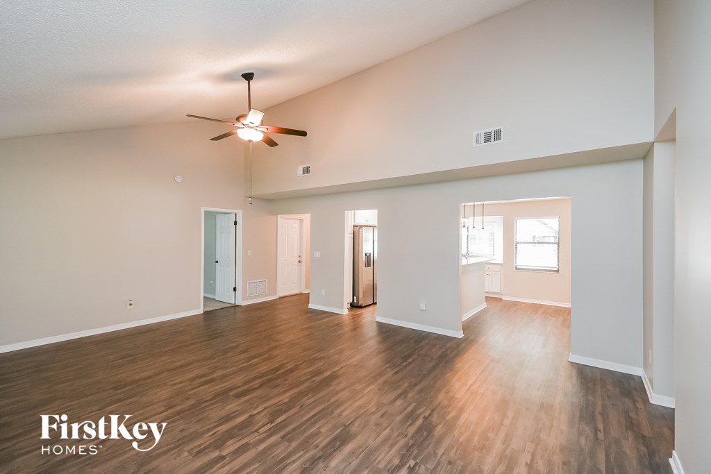 A spacious room with wooden flooring and a ceiling fan.