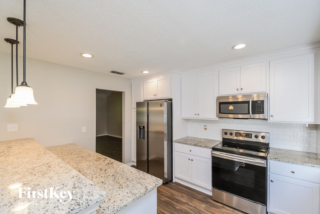 A kitchen with a granite countertop and stainless steel appliances.