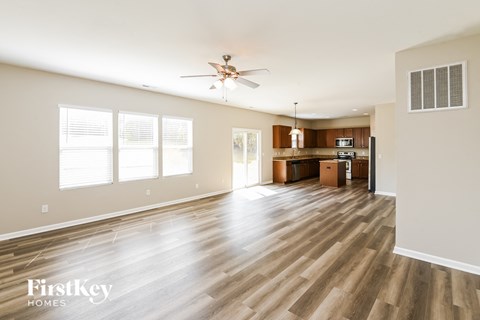 A spacious living room with wooden flooring and a ceiling fan.