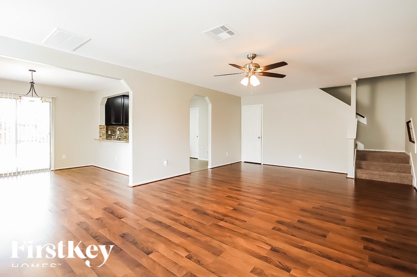 A spacious room with wooden floors and a ceiling fan.