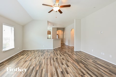 the living room and dining room with wood flooring and ceiling fan
