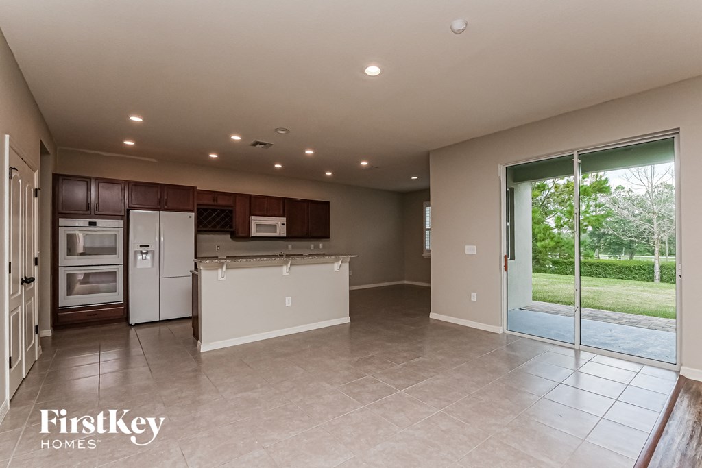 A spacious kitchen and living room with a view of the backyard through the sliding glass doors.