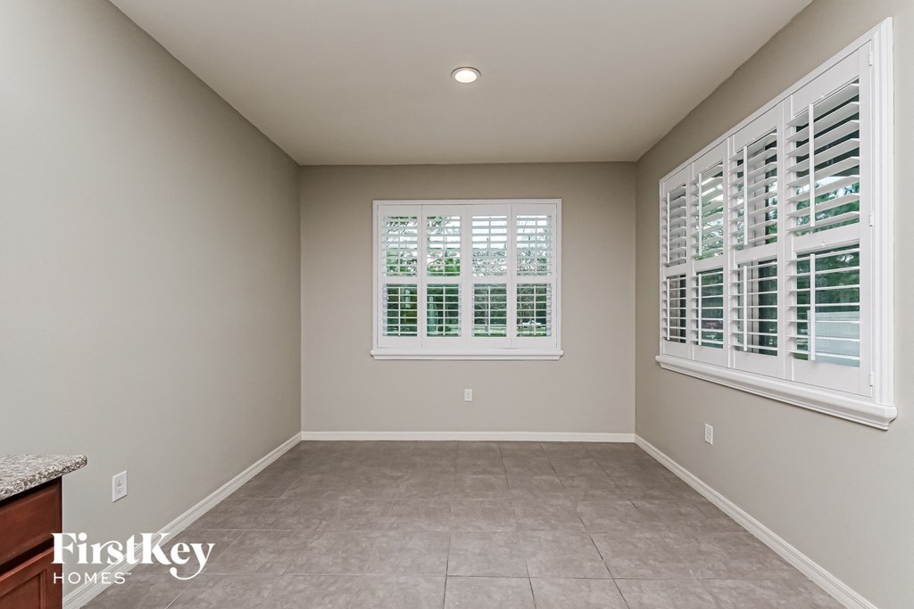 A room with a window covered by white shutters.