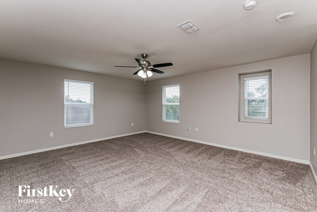 A spacious room with a carpeted floor and a ceiling fan.
