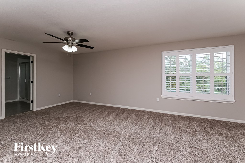 A room with a fan and a window with blinds.