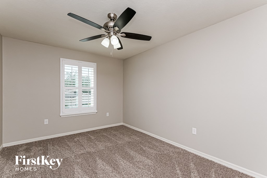 A room with a ceiling fan and a window with blinds.
