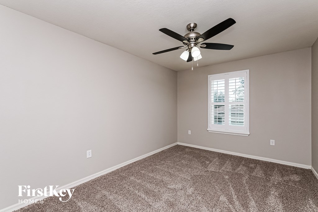 A room with a ceiling fan and a window with blinds.