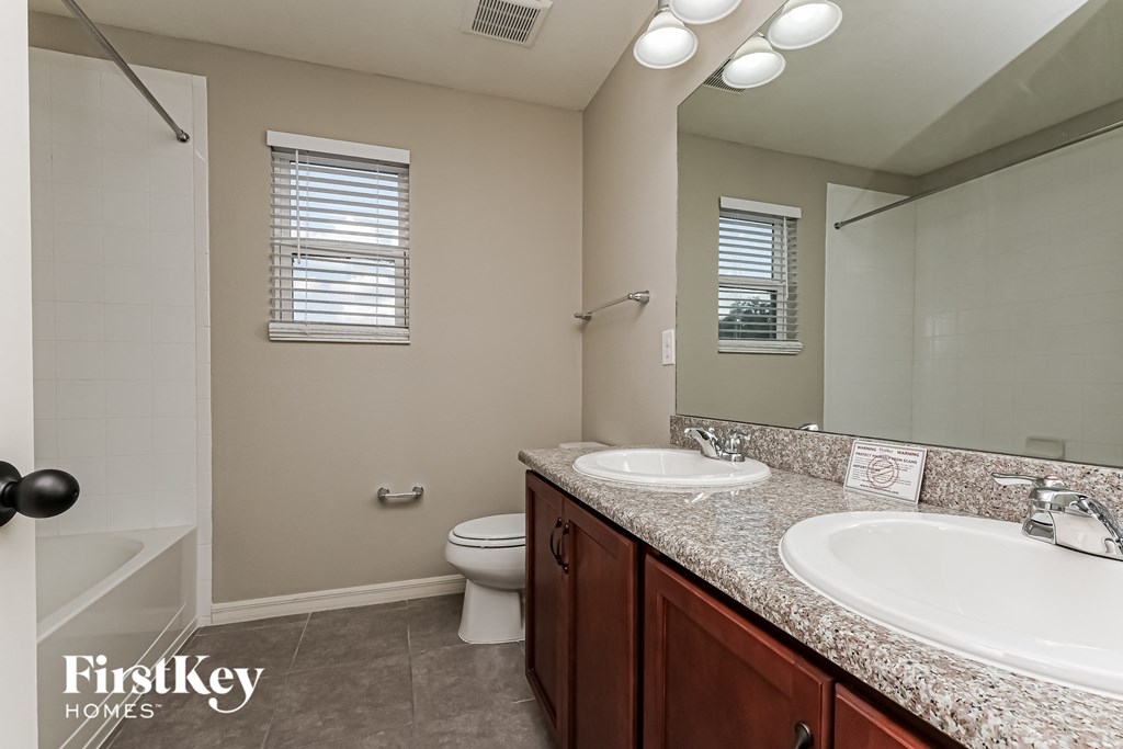 A bathroom with a toilet, sink, and mirror.