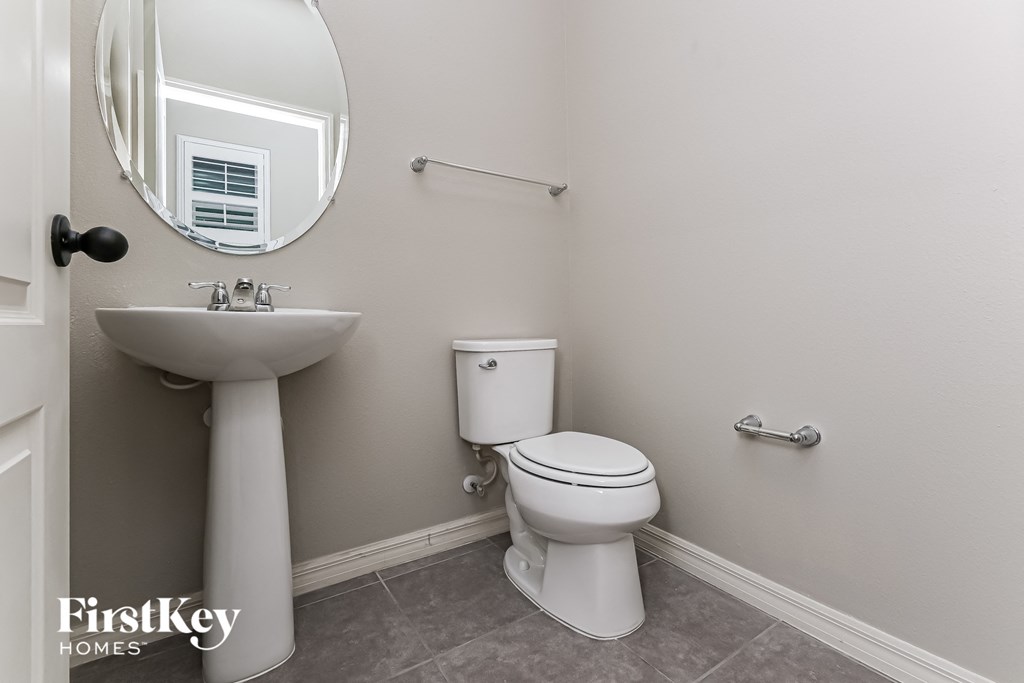 A bathroom with a toilet, sink, and mirror.