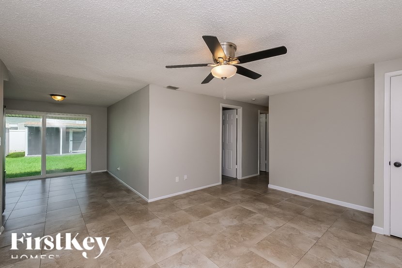 A spacious room with a ceiling fan and tiled flooring.