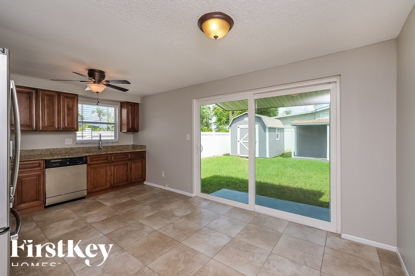 A kitchen with a refrigerator, a ceiling fan, and a sliding glass door that opens to a backyard.