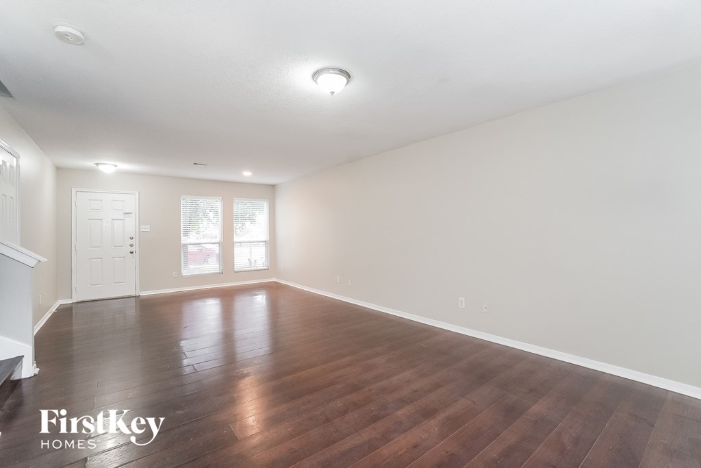 an empty living room with wood floors and white walls