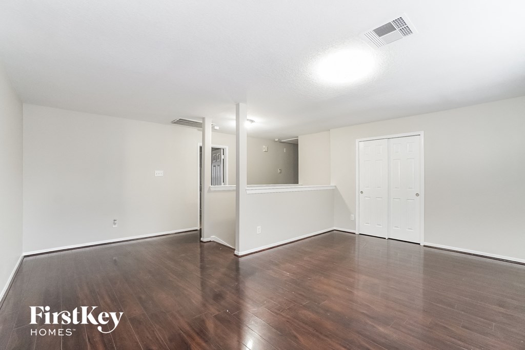 the living room and dining room with wood flooring and white walls
