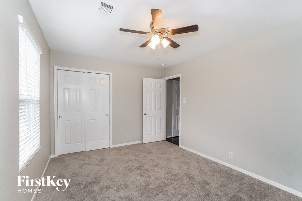 a living room with carpet and a ceiling fan