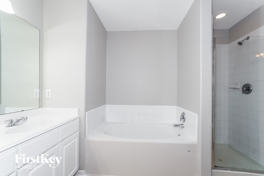 a white bathroom with a tub and a sink and a mirror