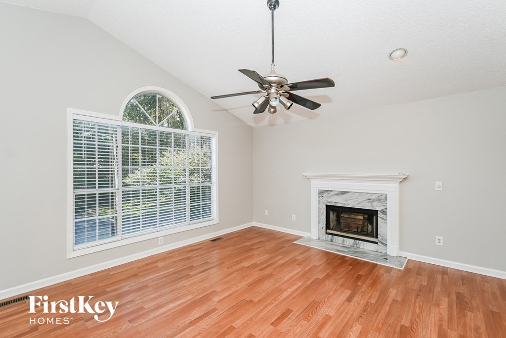 an empty living room with a fireplace and a ceiling fan
