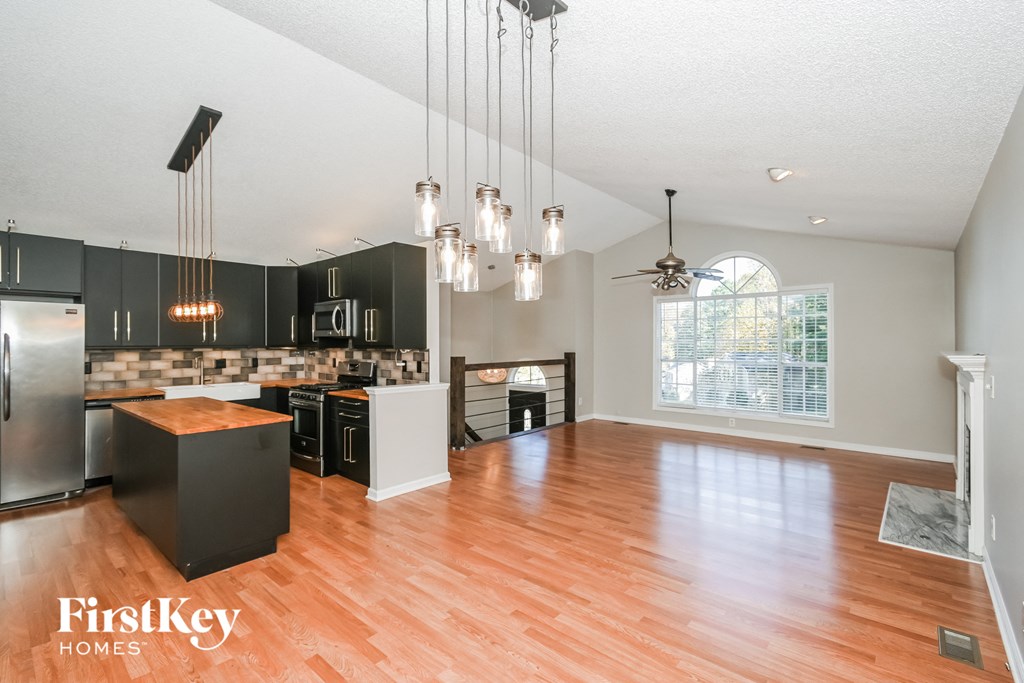 an open kitchen and living room with wood flooring and a large window