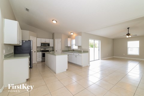 a large kitchen with white cabinets and counters and tiled floors