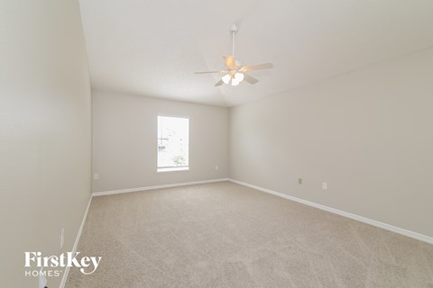 a spacious living room with white carpet and a ceiling fan