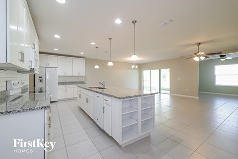 A kitchen with white cabinets and a marble countertop.