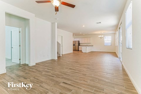 an empty living room and kitchen with a ceiling fan