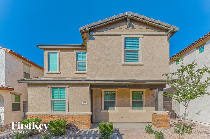 a brick house with green shutters and a sidewalk in front of it