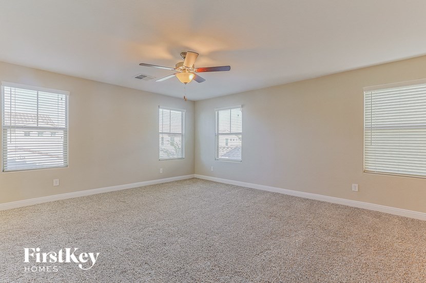 an empty living room with a ceiling fan and two windows