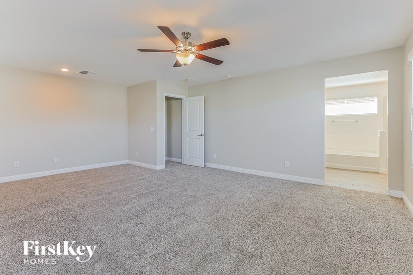 the spacious living room with ceiling fan and carpeting