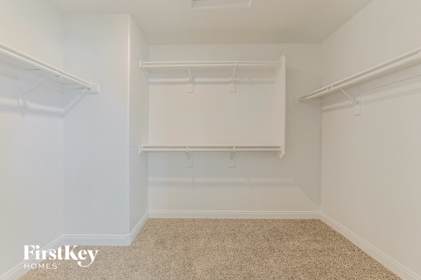 a walk in closet with empty shelves and a white wall