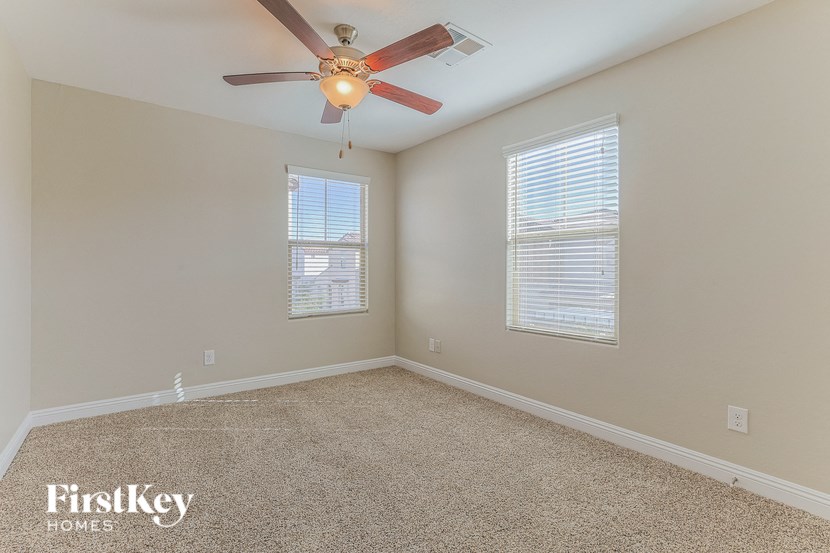 a bedroom with a ceiling fan and two windows