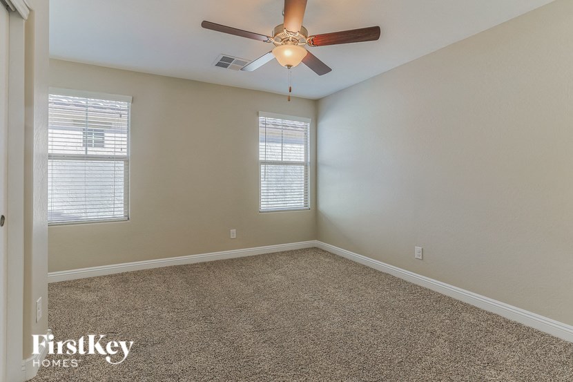 an empty room with a ceiling fan and two windows