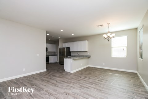 A spacious kitchen and living room with wood flooring and a chandelier.