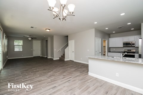 A spacious living room with a kitchen area in the background.